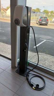 une borne de recharge pour voitures électriques devant une grande baie vitrée