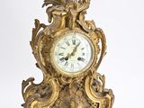 a gold clock that is sitting on a white surface