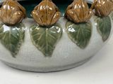 a white and green vase with five small flowers in it
