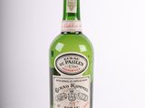 an old bottle of liquor sitting on top of a white surface