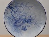 une assiette bleue et blanche posée sur un support, sur une table