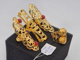 three pairs of gold plated shoes and bracelets on a black box