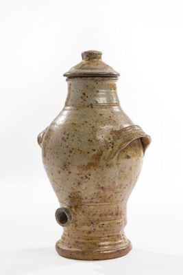 a brown vase with a lid sitting on a white surface