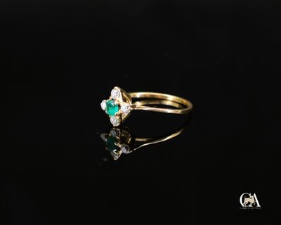 un gros plan d'une bague en or sertie d'une émeraude et d'un diamant blanc