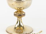 tasse plaquée or avec cuillère et repose-cuillère, posée sur un support blanc