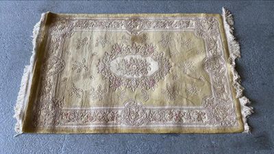 un vieux tapis à franges posé sur une moquette bleue