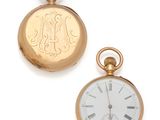two gold pocket watches sitting next to each other on a white surface