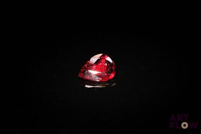 un gros plan d'un diamant rouge en forme de cœur sur une surface noire