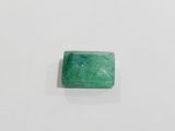 a green emerald stone sitting on top of a white surface