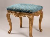 un tabouret ancien dont l'assise est rembourrée de bleu sur fond blanc