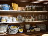 many dishes and cups on the shelves in the cabinet