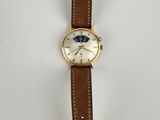 a close up of a watch on a white surface with a brown strap