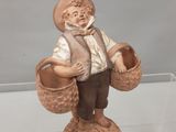 une figurine représentant un homme portant des paniers, posée sur un socle