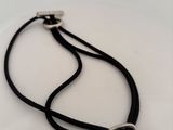 a close up of a black cord necklace with a silver clasp