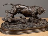 bronze statue of a dog running on a rock with a bird in its mouth