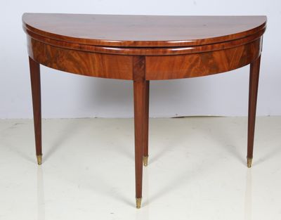 an oval mahogany table with brass legs and a curved top