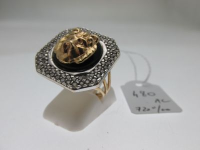 une image représentant une bague dorée et noire ornée d'une tête de lion