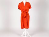 une robe orange posée sur un présentoir à mannequin, sur fond blanc