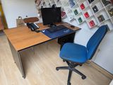 un bureau avec un ordinateur et une chaise bleue dans un coin