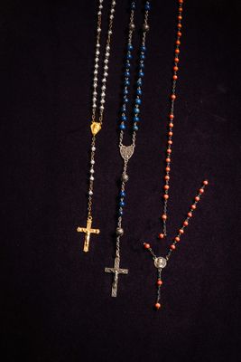 three rosary necklaces on a black background