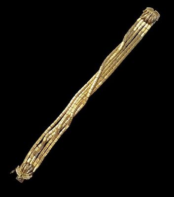 a close up of a gold bracelet on a black background