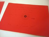 two red papers with writing on them sitting on a table