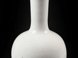 un vase blanc posé sur une surface noire