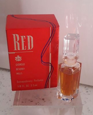 un flacon de parfum posé sur un comptoir à côté d'une boîte rouge