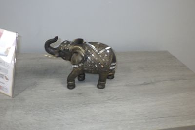 une statue d'éléphant posée sur une table, à côté d'un panneau