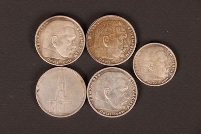 five different coins are arranged in a row on a black surface