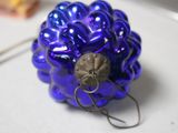 a blue glass ornament on a table with a hook