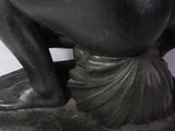 statue of a woman sitting on a rock with her hands on her hips