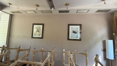a room with a bunch of wooden chairs and a painting on the wall