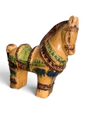 un cheval en céramique posé sur une surface blanche