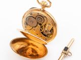 an image of a gold pocket watch with a key on a white background