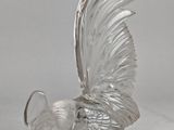 une sculpture en verre transparent représentant un oiseau, posée sur une table
