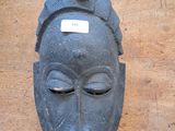 a black mask on a wooden table with a tag on it