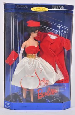 La poupée se trouve dans la boîte, vêtue d'un manteau rouge et d'une robe blanche.