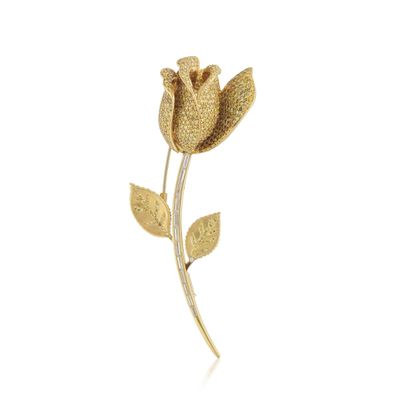 un gros plan d'une broche en forme de fleur dorée sur fond blanc