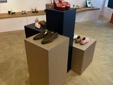 Plusieurs paires de chaussures sont exposées dans une pièce au sol en parquet.