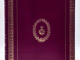 a red book with gold trim and a wreath on the cover