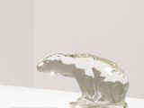 sculpture représentant un ours polaire posée sur un socle blanc devant un mur blanc
