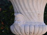 a white vase sitting on top of a stone pedestal