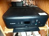 a black printer sitting on top of a wooden shelf