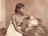 an old photo of a woman with a vase on a hay pile