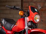 a red motorcycle parked in front of a brick wall