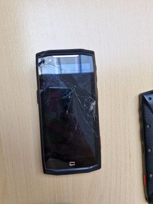 un téléphone portable cassé et un portefeuille abîmé posés sur une table