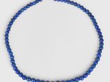 a close up of a blue beaded necklace on a white background