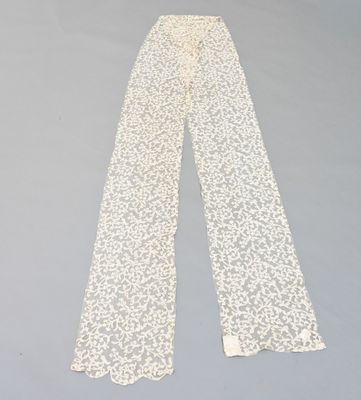 un pantalon en dentelle blanche posé sur une surface grise