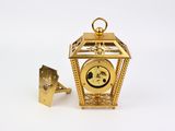 a small gold clock with a golden bell on it